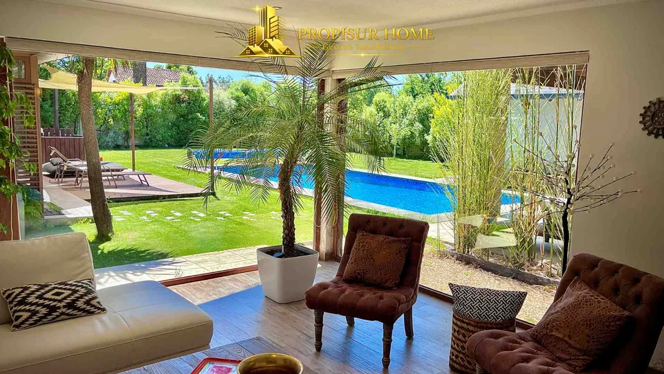 Vista desde el living hacia la terraza, jardín y piscina en casa exclusiva en venta en Angol