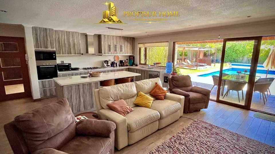 Sala de estar integrada con cocina moderna y vista a la piscina en casa exclusiva en venta en Angol