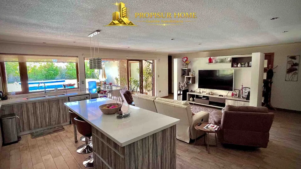 Cocina moderna integrada con living y vista a la piscina en casa exclusiva en venta en Angol