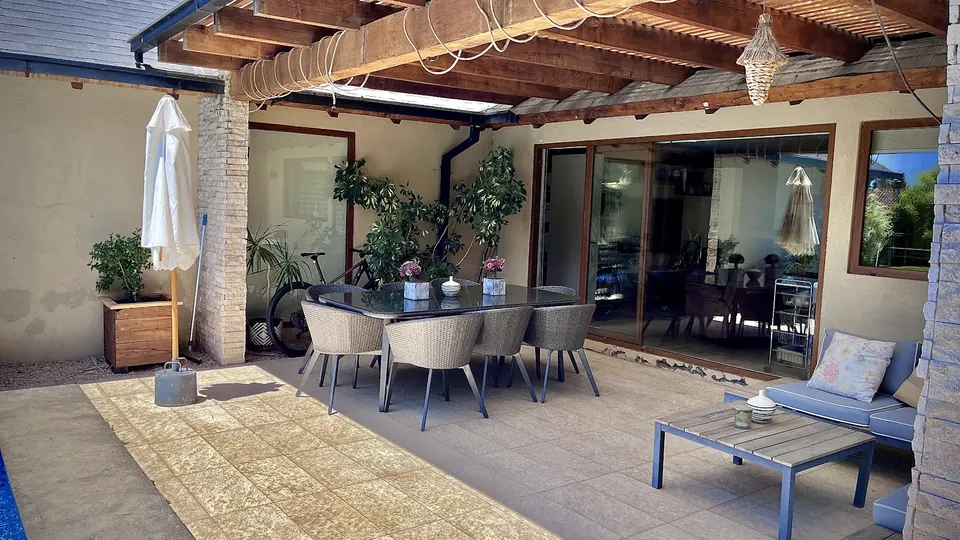 Terraza techada con comedor exterior junto al jardín